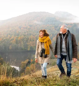 Retired couple holding hands walking through the hills
