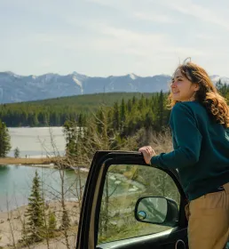 Woman climbing out of car looking out at landscape