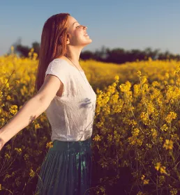 Joyful girl enjoying sunshine in flower field