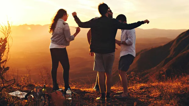 four friends standing on grassy mountain