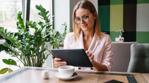 business woman sitting in a coffee shop on a tablet business woman sitting in a coffee shop on a tablet