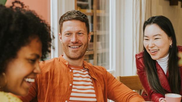 Three friends drinking coffee and smiling