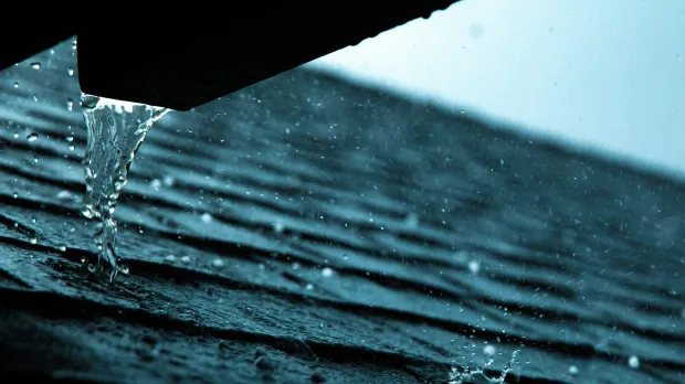 Excess water falls from gutters onto a roof