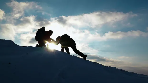 Travelers climb together up mountain. 