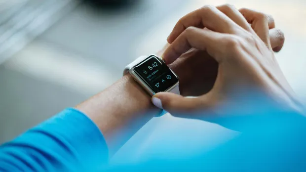 Smartwatch Health Tracking Person adjusting a smartwatch displaying time and health data on their wrist