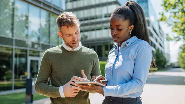 Asset managers sustainability disclosures Man and woman looking at tablet with greenery background