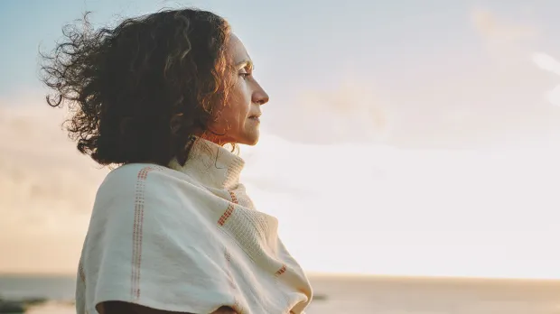Woman looking forebodingly out to sea at sunset