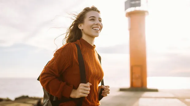 Young female hiking in front of a lighthouse