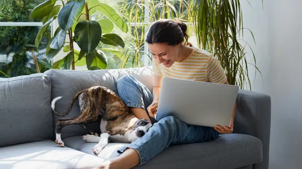 Woman working from home with dog on sofa