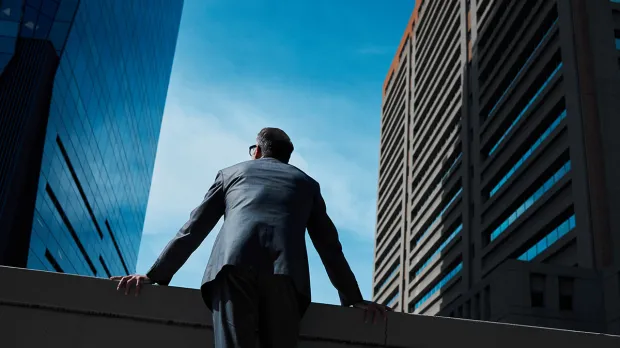 Man in suit looking at blue sky between London skyscrapers