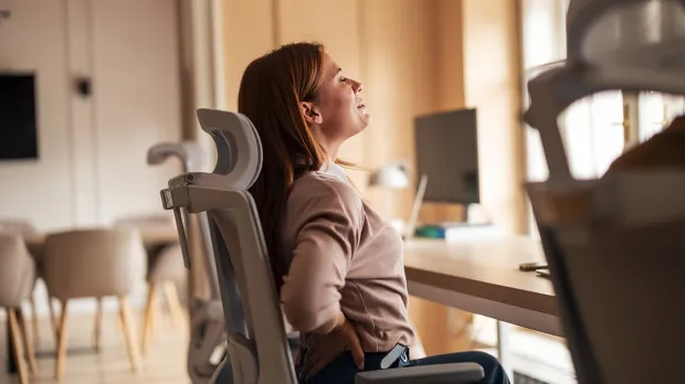 Supporting colleagues with chronic conditions Woman with back issues in desk chair
