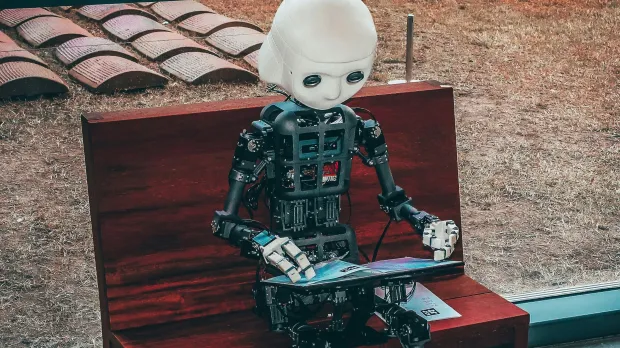 AI robot on a bench with laptop