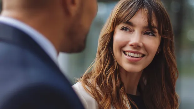 Female colleague listening to male and smiling