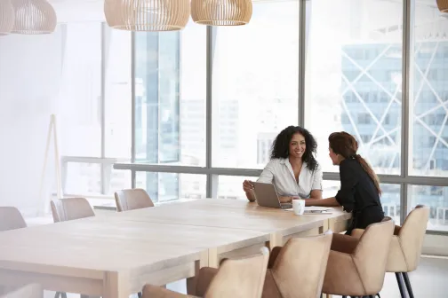 Two business women have a meeting in a brightly lit modern office