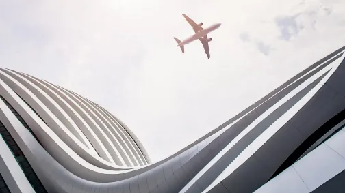plane flying over modern building