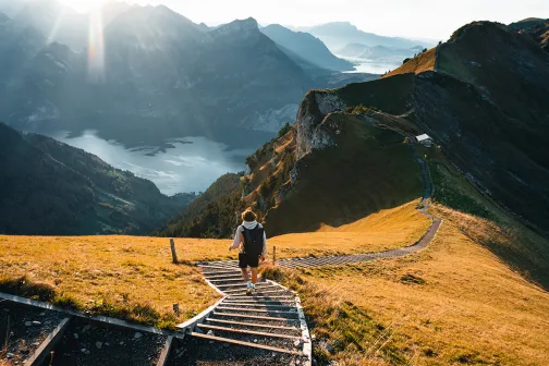 Hiker walking down steps through valley and mountain landscape