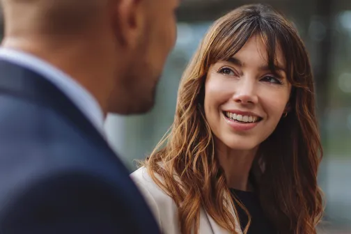 Female colleague listening to male and smiling