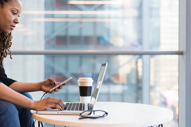 female drinking takeaway coffee working on laptop