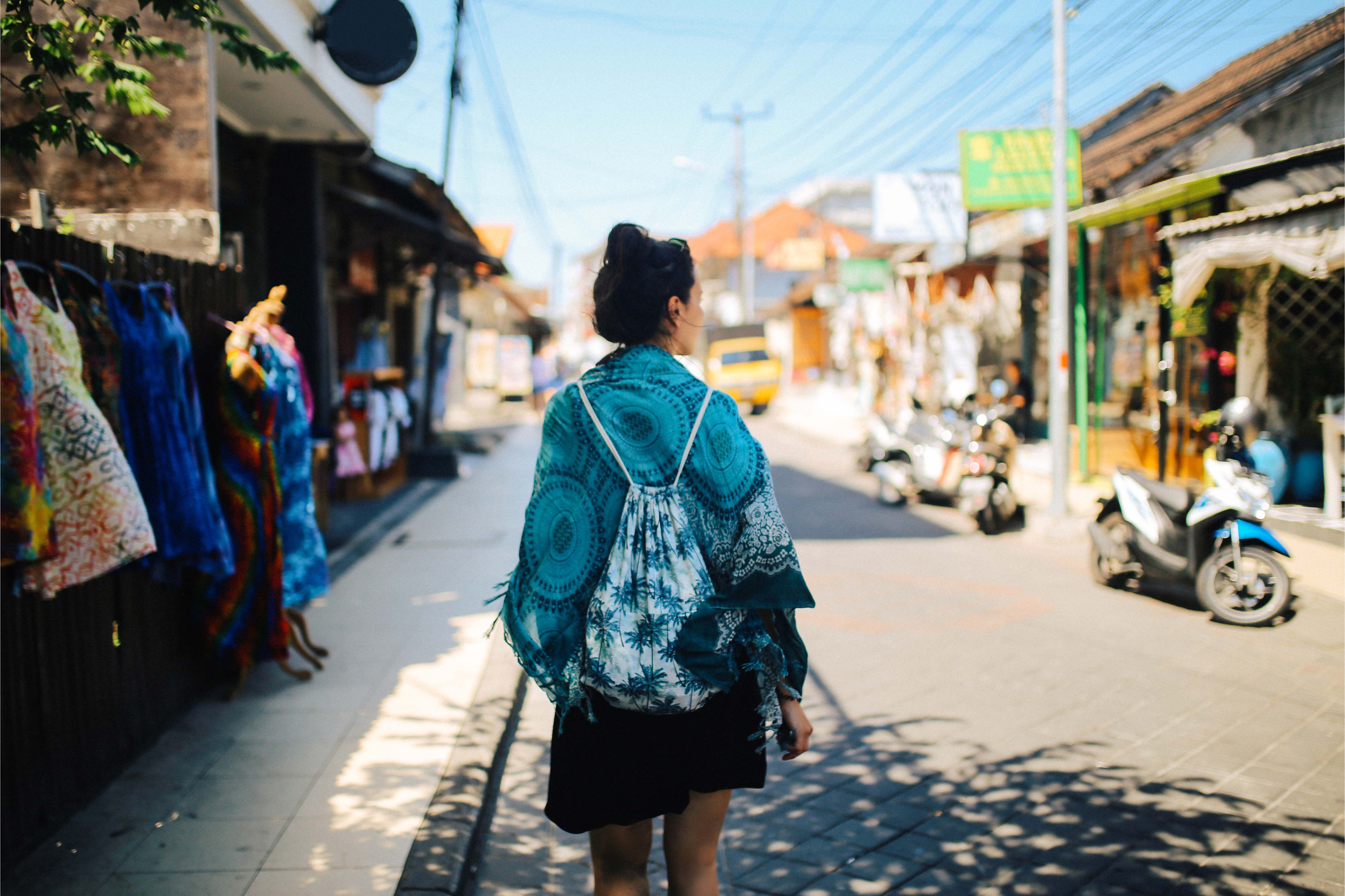 Woman walking through a colourful Indonesian street market in the sunshine