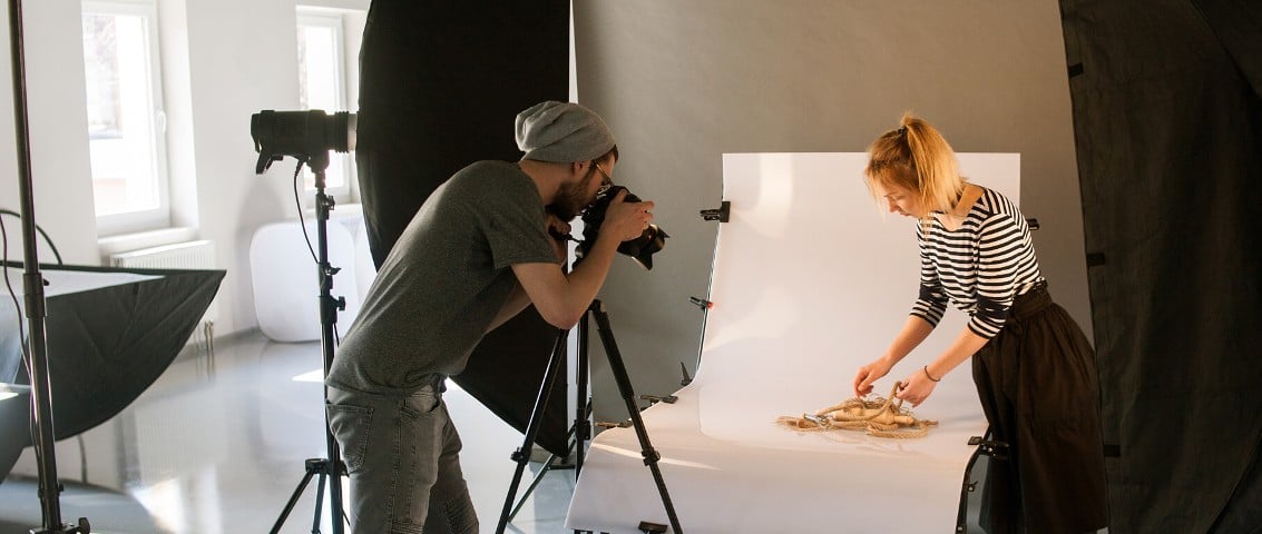 A person taking a photo of a woman in a studio
