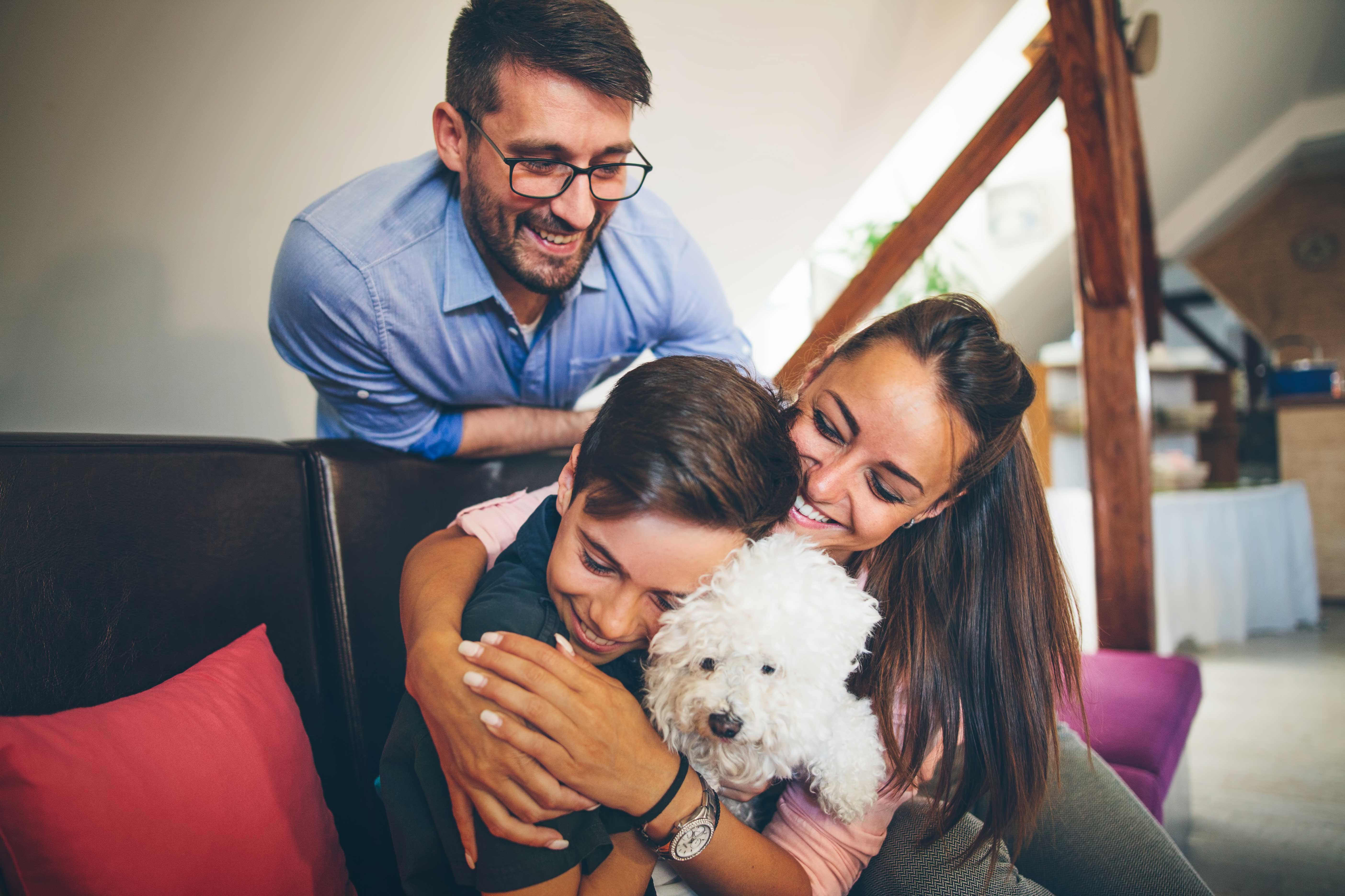 Family hugging their dog on a couch