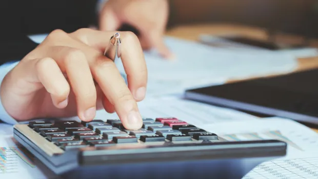 Close up of hand holding a pen and using a calculator