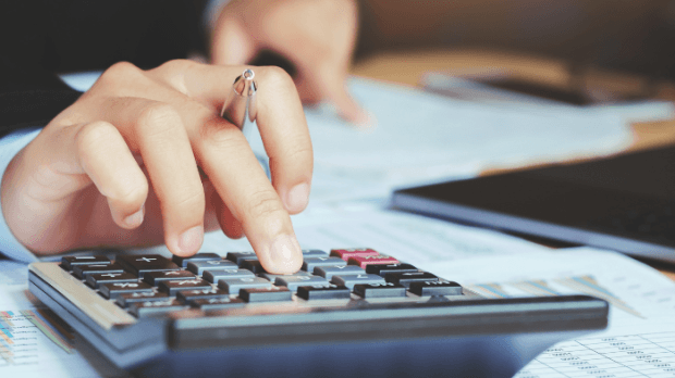 Close up of hand holding a pen and using a calculator
