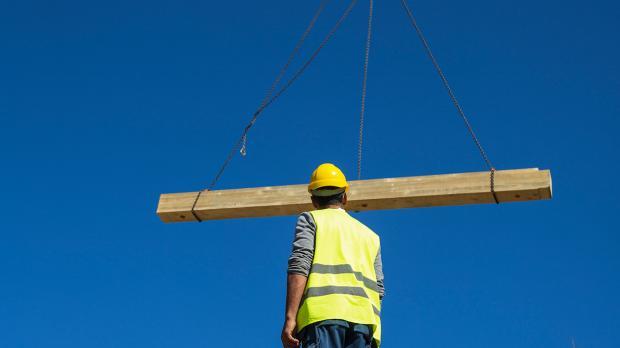 Engineer in a construction site watching a crane with a log