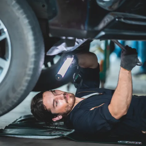 Mechanic inspecting a vehicle with a flashlight
