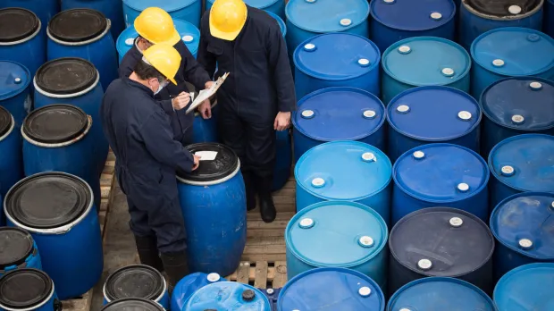 Two men inspecting a large amount of blue barrels