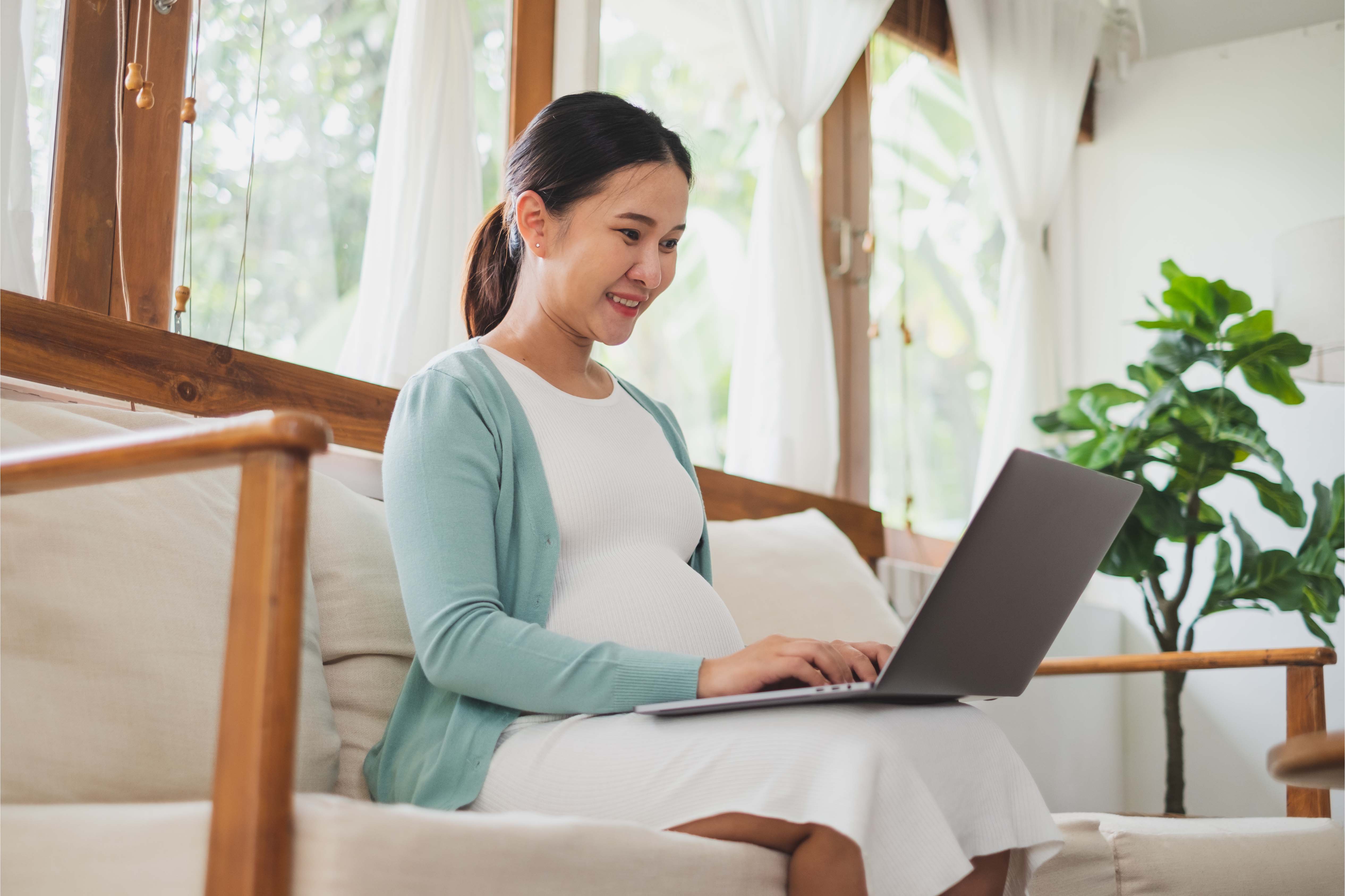 Asian pregnant woman using laptop computer at home