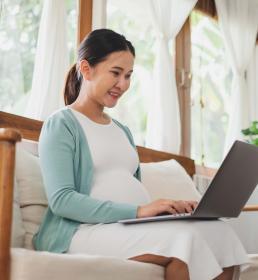 Asian pregnant woman using laptop computer at home