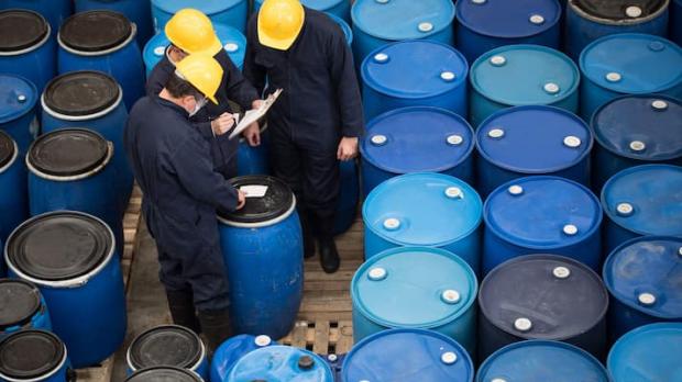 Two men inspecting a large amount of blue barrels