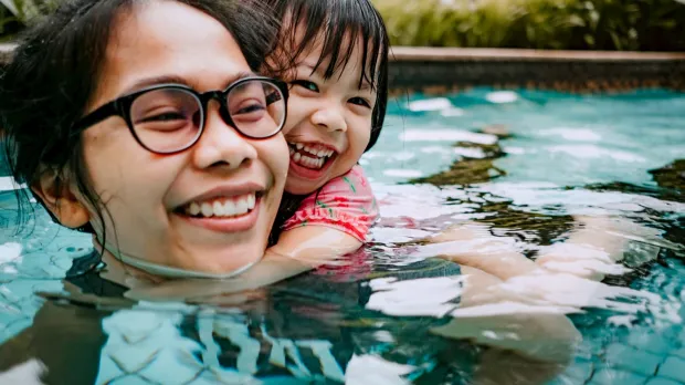 Smiling mother in pool with her daughter