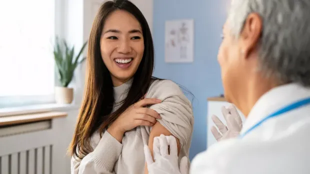 Smiling woman at a clinic receiving a vaccination from a medical professional