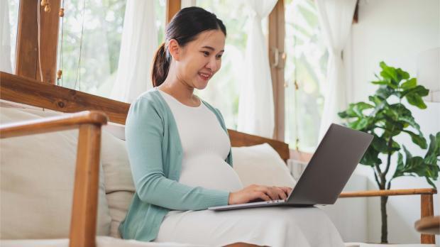 Asian pregnant woman using laptop computer at home