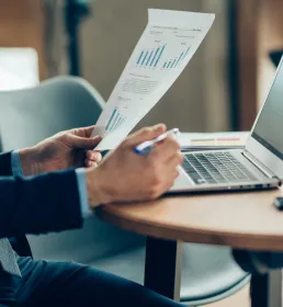 A financial accountant reviews a page of figures while using his laptop