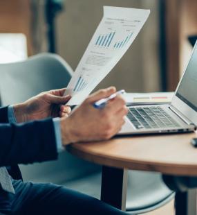 A financial accountant reviews a page of figures while using his laptop