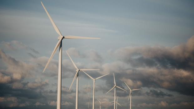 Five wind turbines on a hill against a clouded sky