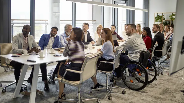 Large group of professional people sat around a board room table Large group of professional people sat around a board room table