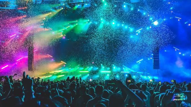 Rainbow lighting illuminating crowd at large live event