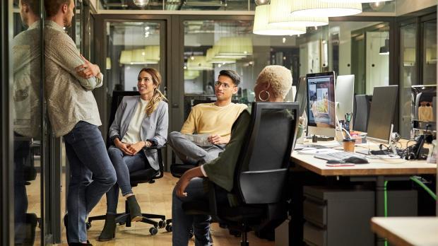 Team sitting and talking at their desks