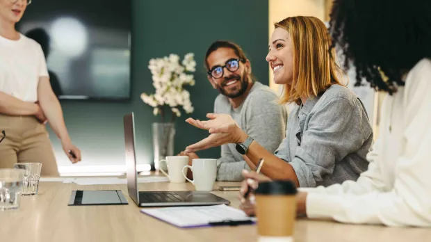 Colleagues sitting at meeting table laughing together