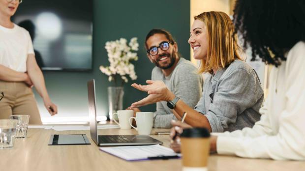Colleagues sitting at meeting table laughing together