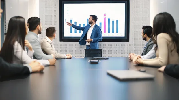 Financial advice presentation man showing graph to table full of people
