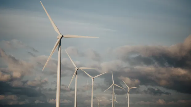 Five wind turbines on a hill against a clouded sky