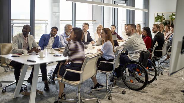 Large group of professional people sat around a board room table
