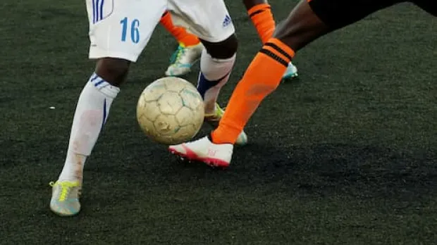 footballers tackling and kicking a ball 