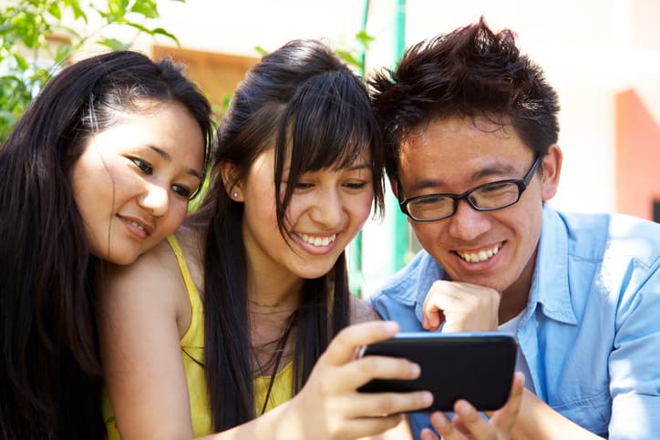 Young Filipino workers gathered around a mobile phone looking at a picture together