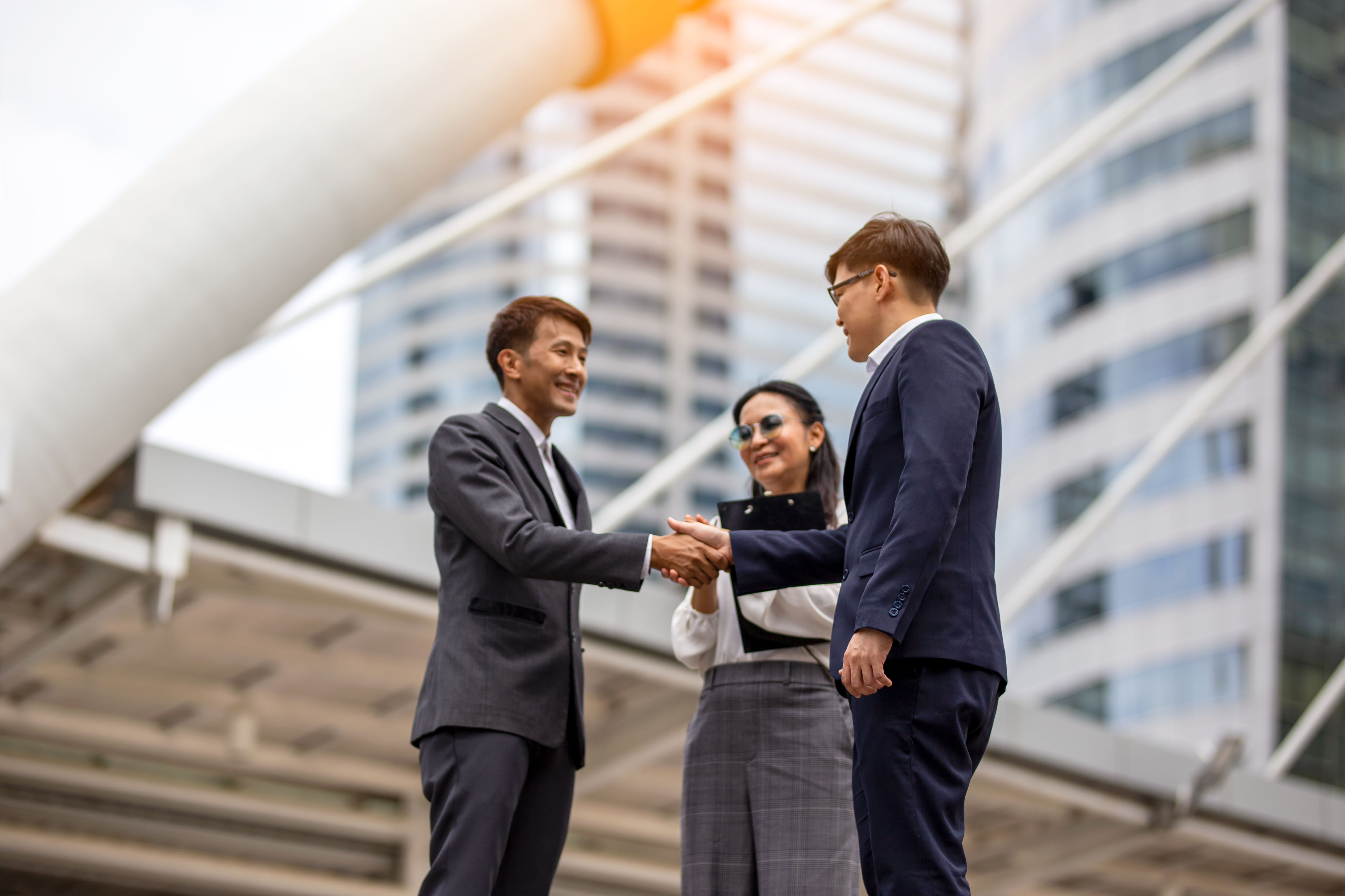 Business professionals shaking hands in a modern city setting, symbolising leadership, trust, and key person protection.